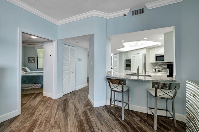 kitchen featuring sink, a breakfast bar area, white cabinets, stainless steel appliances, and light stone countertops