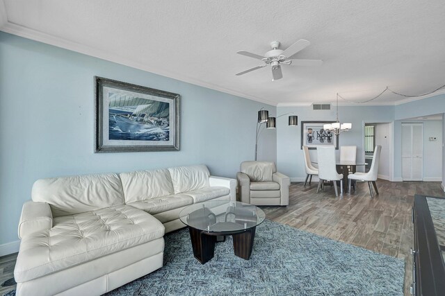 living room featuring wood-type flooring, ceiling fan with notable chandelier, a textured ceiling, and crown molding