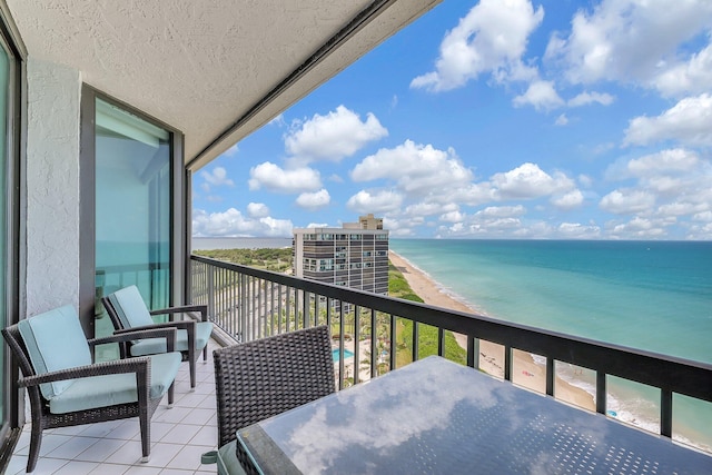 balcony featuring a view of the beach and a water view