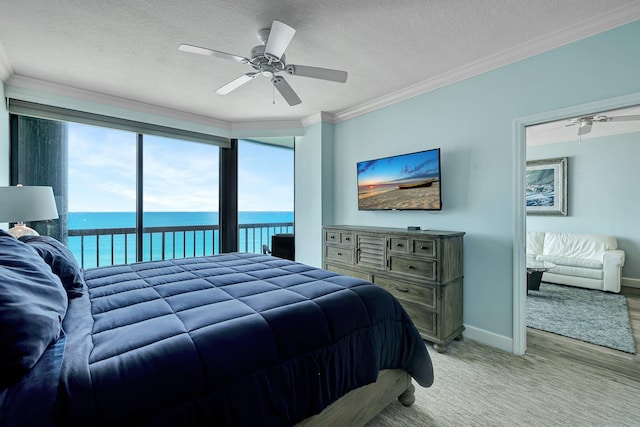 bedroom featuring ornamental molding, a water view, access to outside, and a textured ceiling