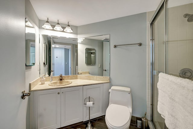 bathroom featuring vanity, toilet, and a shower with shower door