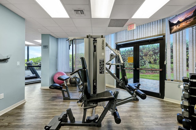 workout area featuring french doors, a paneled ceiling, and wood-type flooring