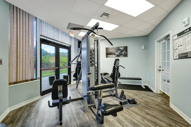 workout area featuring a drop ceiling, hardwood / wood-style floors, and french doors