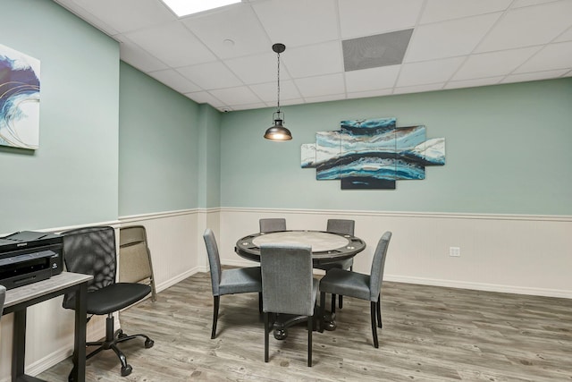 dining area with a drop ceiling and wood-type flooring