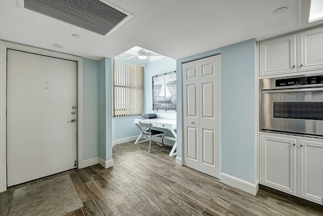 kitchen featuring white cabinetry, wood-type flooring, stainless steel oven, and ceiling fan