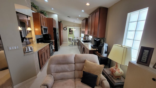 kitchen featuring light tile patterned flooring, lofted ceiling, tasteful backsplash, stainless steel appliances, and pendant lighting