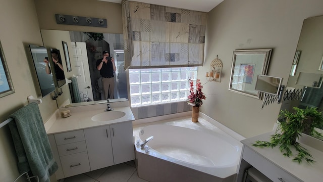 bathroom with a tub, vanity, and tile patterned flooring