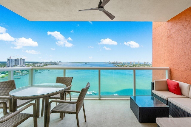 balcony featuring an outdoor living space, a water view, and ceiling fan