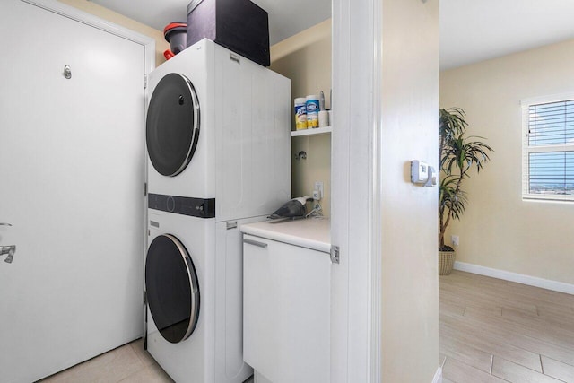 clothes washing area with light wood-type flooring and stacked washer / drying machine