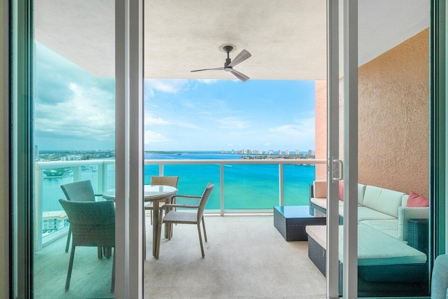 balcony with ceiling fan, a water view, and an outdoor living space