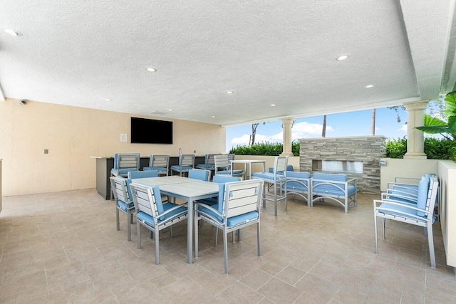 dining room featuring floor to ceiling windows, decorative columns, and a textured ceiling