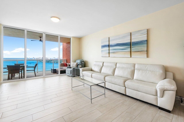 living room featuring a wall of windows, a water view, and light wood-type flooring