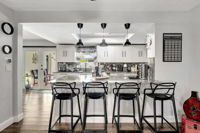 kitchen featuring white cabinetry, tasteful backsplash, kitchen peninsula, and light wood-type flooring