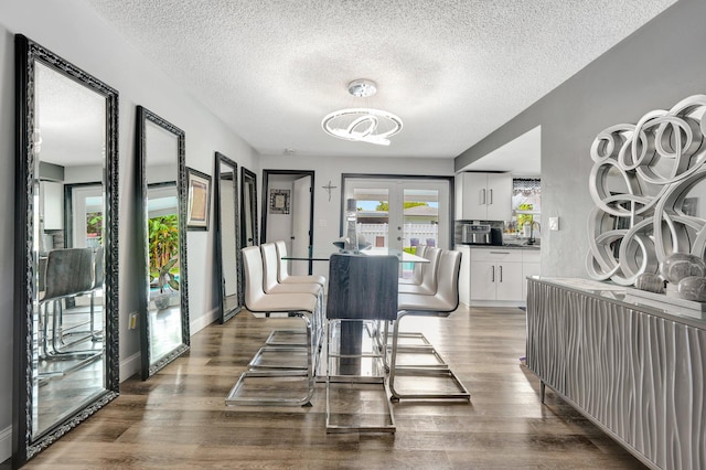 dining area with sink, a textured ceiling, french doors, and wood-type flooring