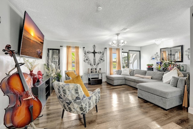 living room with a textured ceiling, hardwood / wood-style floors, and a chandelier