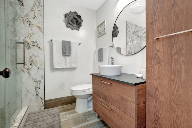 bathroom featuring vanity, toilet, and a tile shower