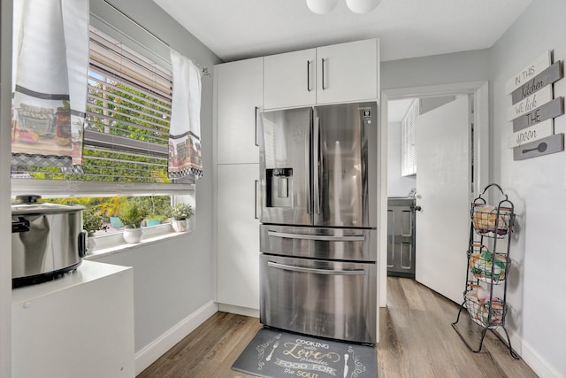 kitchen with white cabinets, stainless steel fridge, and hardwood / wood-style floors