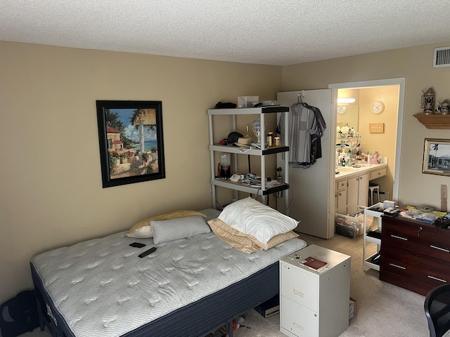 bedroom featuring connected bathroom, light carpet, and a textured ceiling