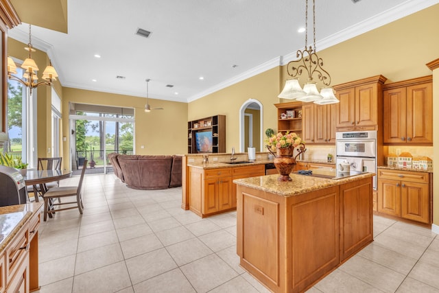 kitchen with sink, a center island, light stone countertops, double oven, and backsplash