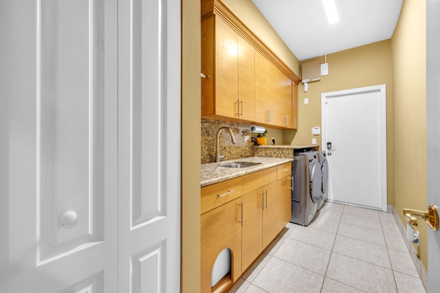 washroom featuring cabinets, sink, washer and dryer, and light tile patterned floors