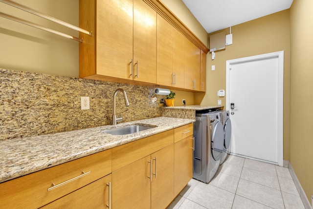 laundry room with light tile patterned flooring, cabinets, washer and dryer, and sink