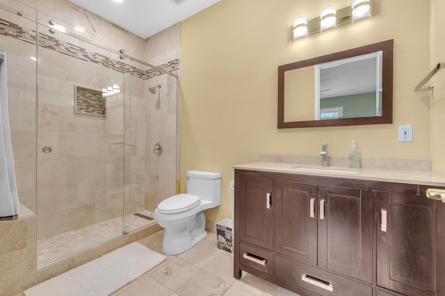 bathroom with tile patterned floors, vanity, a tile shower, and toilet