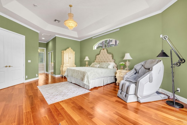 bedroom with crown molding, a raised ceiling, and hardwood / wood-style floors