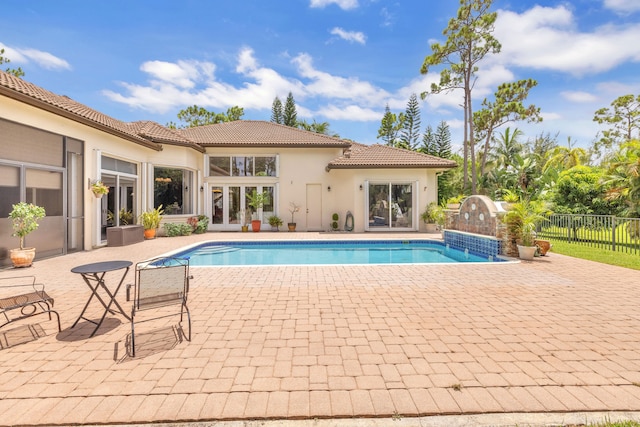 view of pool with french doors, pool water feature, and a patio area