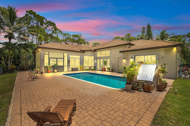 pool at dusk with a patio area