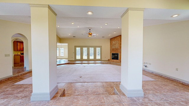 unfurnished living room with light tile patterned floors, lofted ceiling, ornate columns, a large fireplace, and ceiling fan