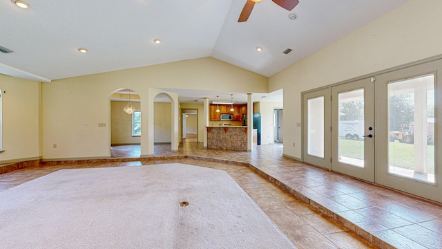 unfurnished living room with high vaulted ceiling, light tile patterned floors, french doors, and ceiling fan