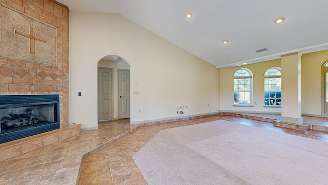 unfurnished living room featuring a fireplace, tile walls, lofted ceiling, and light tile patterned floors