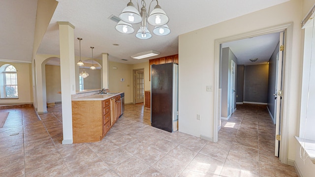 kitchen with sink, hanging light fixtures, fridge, light tile patterned floors, and a notable chandelier