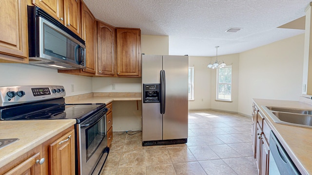 kitchen with light tile patterned flooring, a textured ceiling, an inviting chandelier, stainless steel appliances, and decorative light fixtures