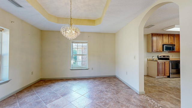 empty room with sink, light tile patterned floors, a raised ceiling, and a chandelier