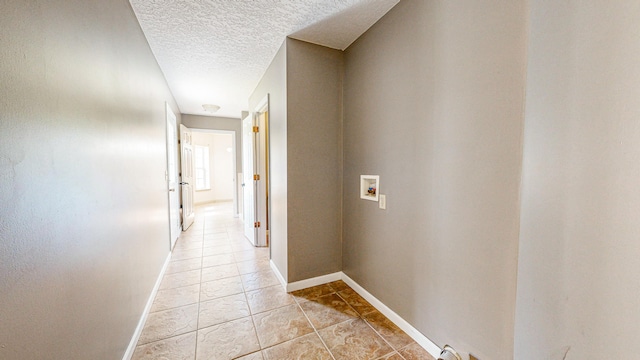 hall featuring a textured ceiling and light tile patterned floors