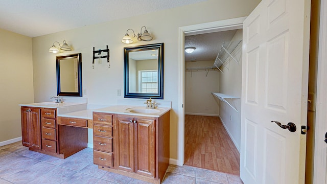 bathroom with tile patterned flooring, a textured ceiling, and dual bowl vanity