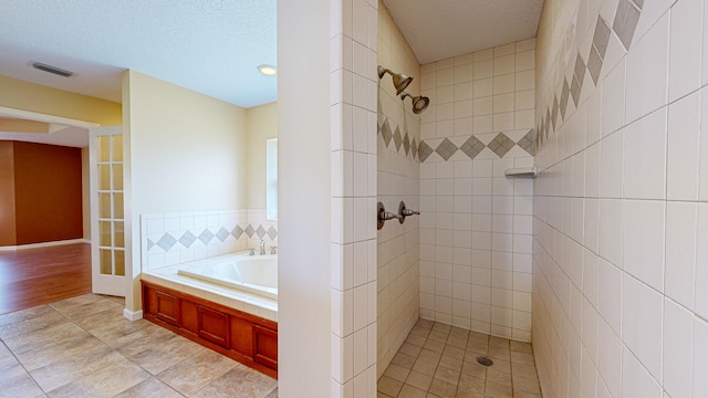 bathroom with plus walk in shower, a textured ceiling, and hardwood / wood-style flooring