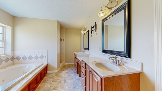 bathroom featuring a tub to relax in, tile patterned floors, a textured ceiling, and double sink vanity