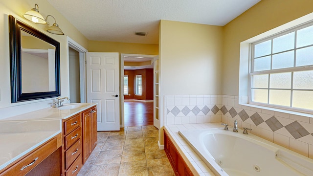 bathroom featuring tiled bath, hardwood / wood-style floors, vanity, and a textured ceiling