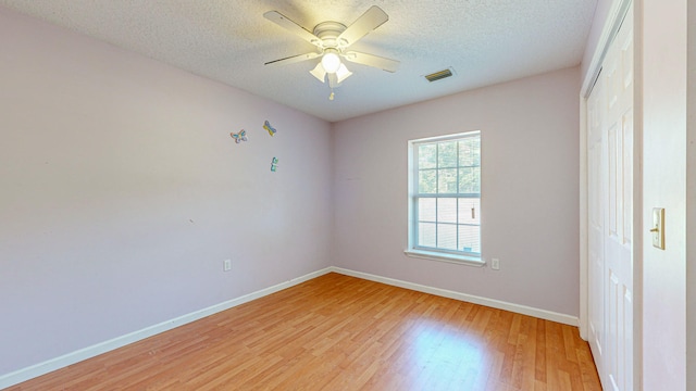 empty room with ceiling fan, a textured ceiling, and light hardwood / wood-style flooring