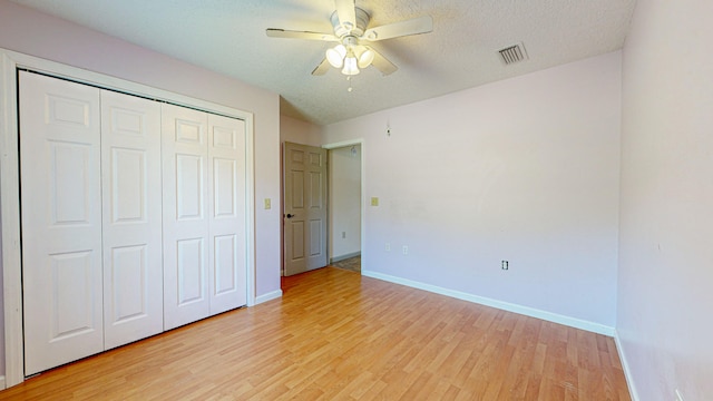 unfurnished bedroom featuring a closet, a textured ceiling, ceiling fan, and light wood-type flooring