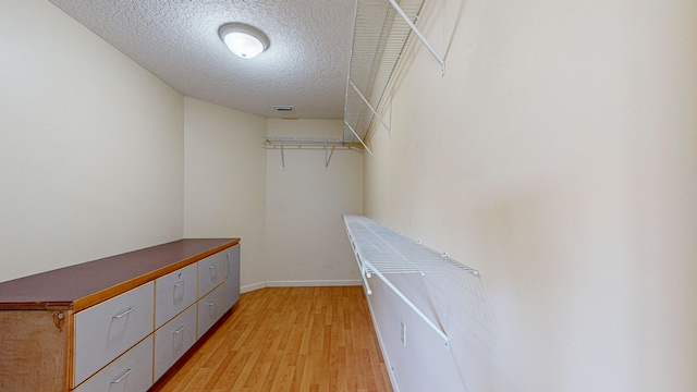 walk in closet with light hardwood / wood-style floors