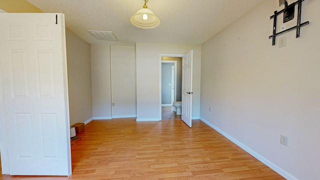 empty room with a textured ceiling and light wood-type flooring