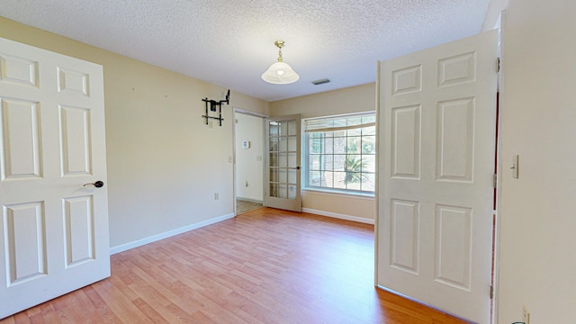 unfurnished bedroom featuring light wood-type flooring and a textured ceiling