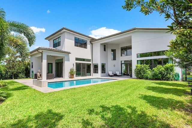 back of property with a patio, a lawn, an outdoor pool, and stucco siding