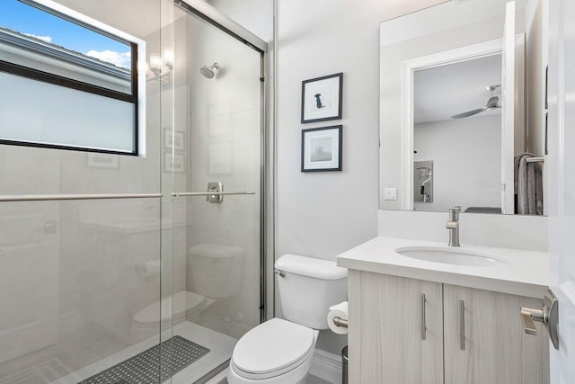 bathroom featuring vanity, walk in shower, toilet, and ceiling fan