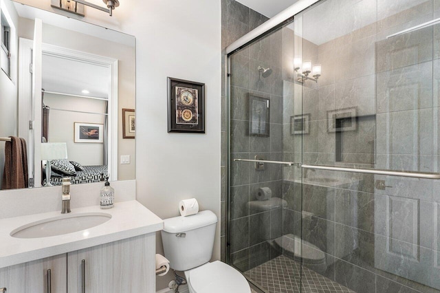 bathroom featuring toilet, an enclosed shower, and vanity