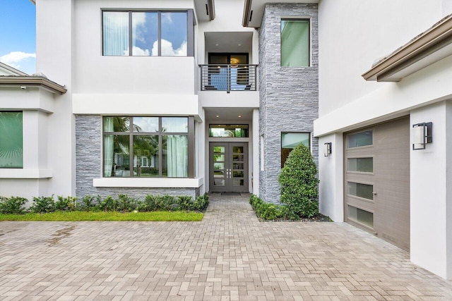 view of exterior entry with french doors and a balcony