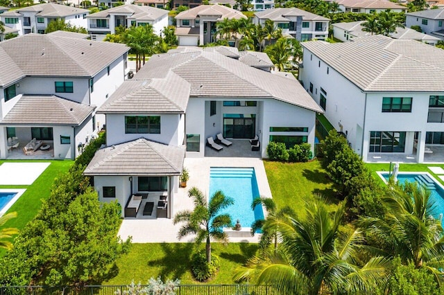 back of house with a fenced in pool, a patio area, and a lawn